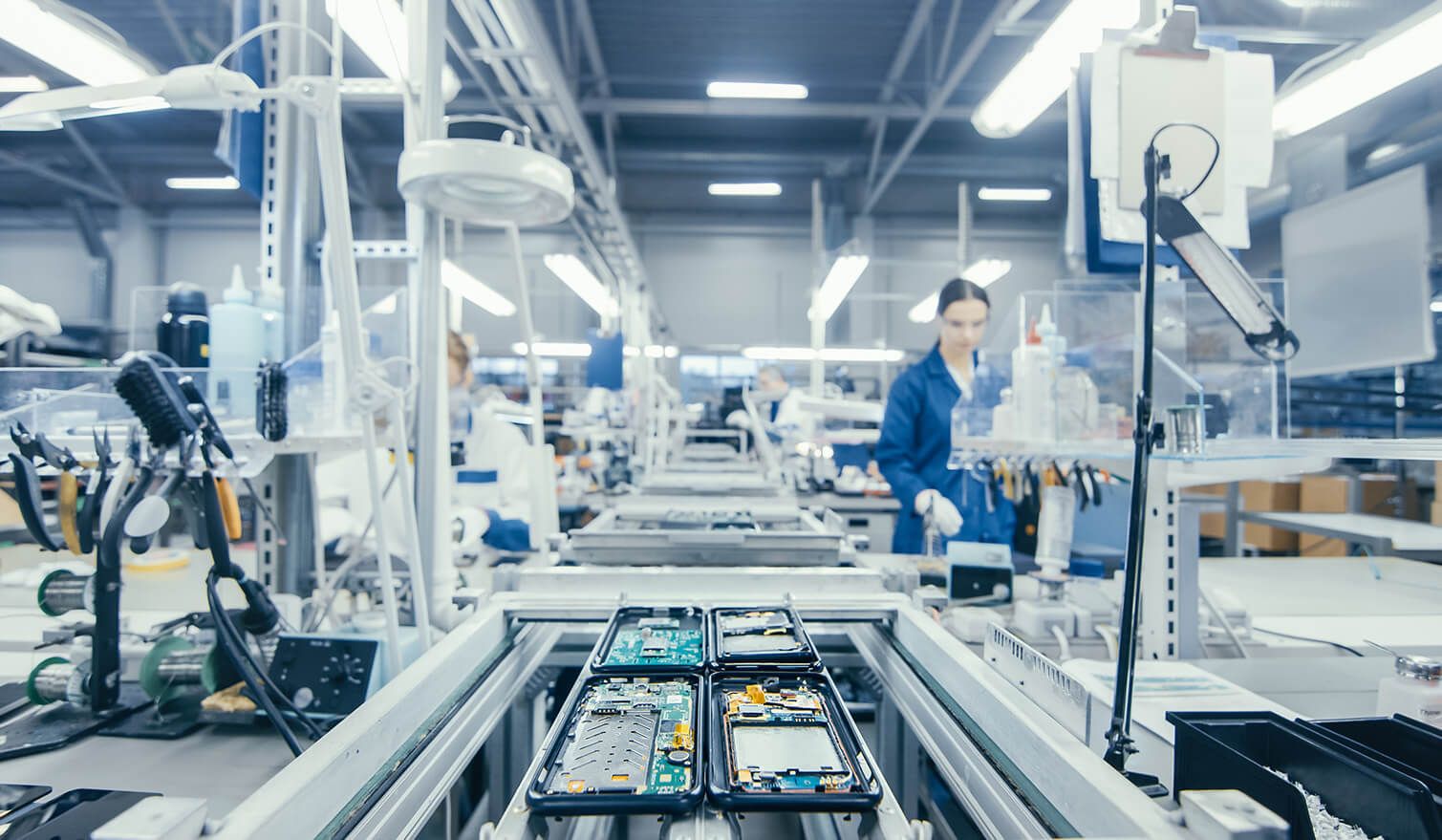Des employés d'une usine de production assemblent des composants électroniques sous un éclairage spécialement conçu à cet effet