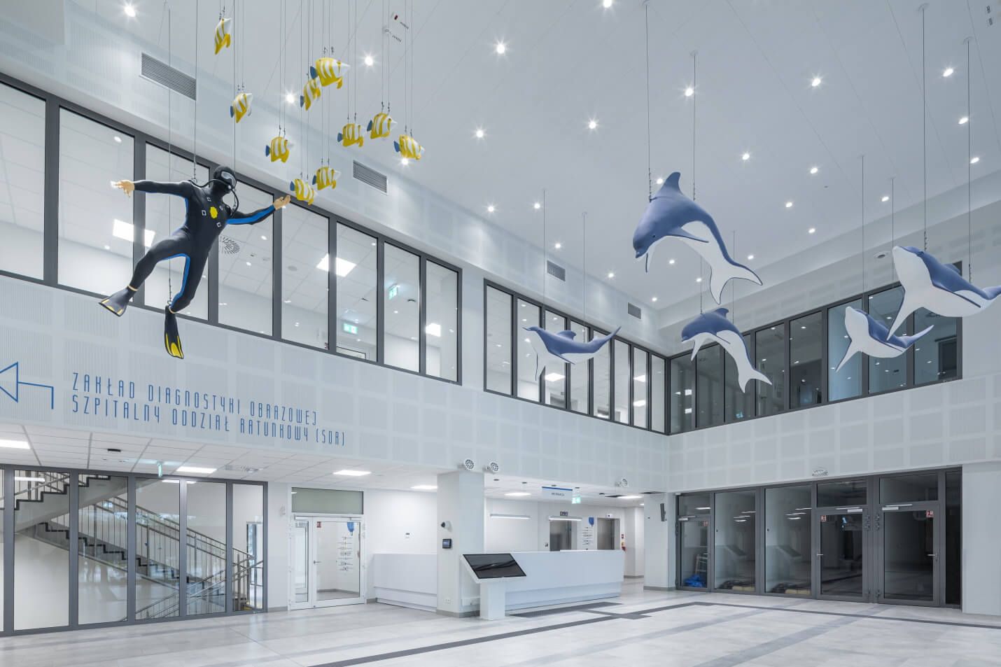 Intérieur lumineux et moderne d'un hôpital, avec une réception, des décorations suspendues en forme de poissons, de dauphins et d'un plongeur, ainsi qu'un éclairage LED moderne | Lumedic