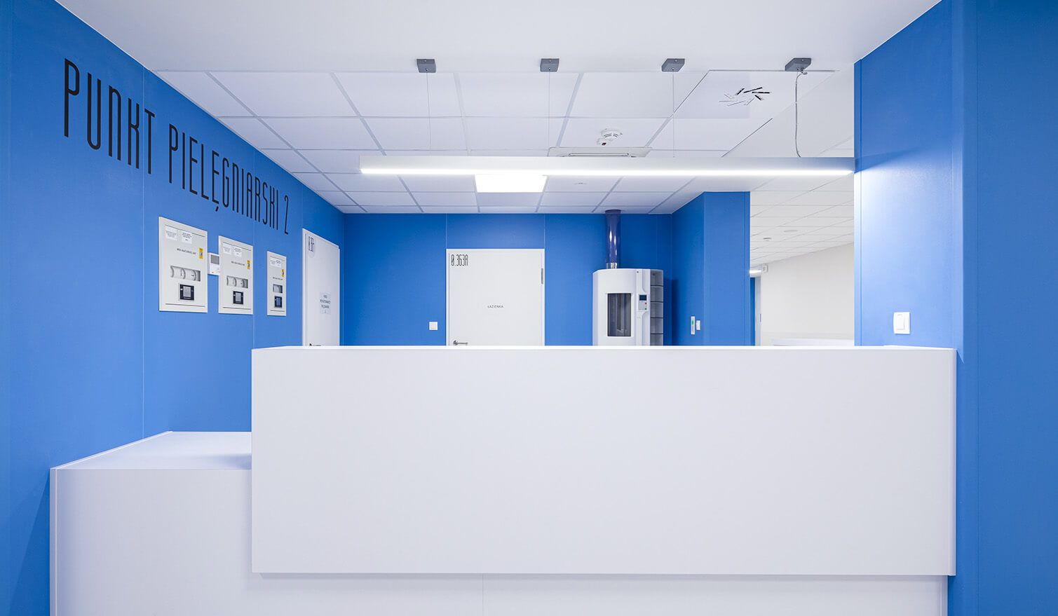 Accueil bleu et blanc avec un comptoir blanc dans un établissement de santé, doté d'un éclairage médical adapté