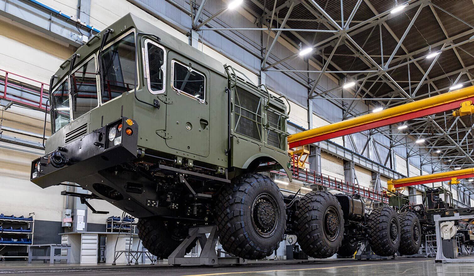 Les employés de l'usine s'affairent à la construction d'un gros véhicule militaire, dans un lieu de travail bien éclairé et bien organisé