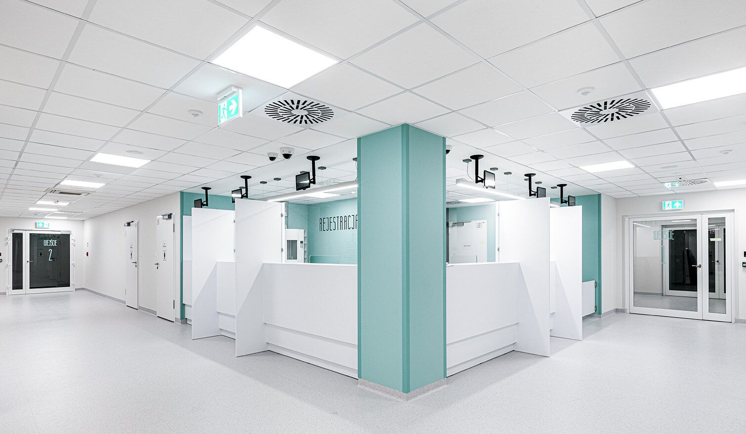 Un couloir d'hôpital avec un plafond blanc et des murs bleus, créant un environnement accueillant et rassurant pour les patients. | Lumedic