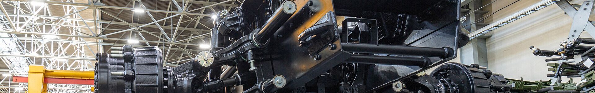 Une grande machine noire et jaune dans une usine, dotée d'un éclairage adapté à la production de précision dans l'industrie de l'armement