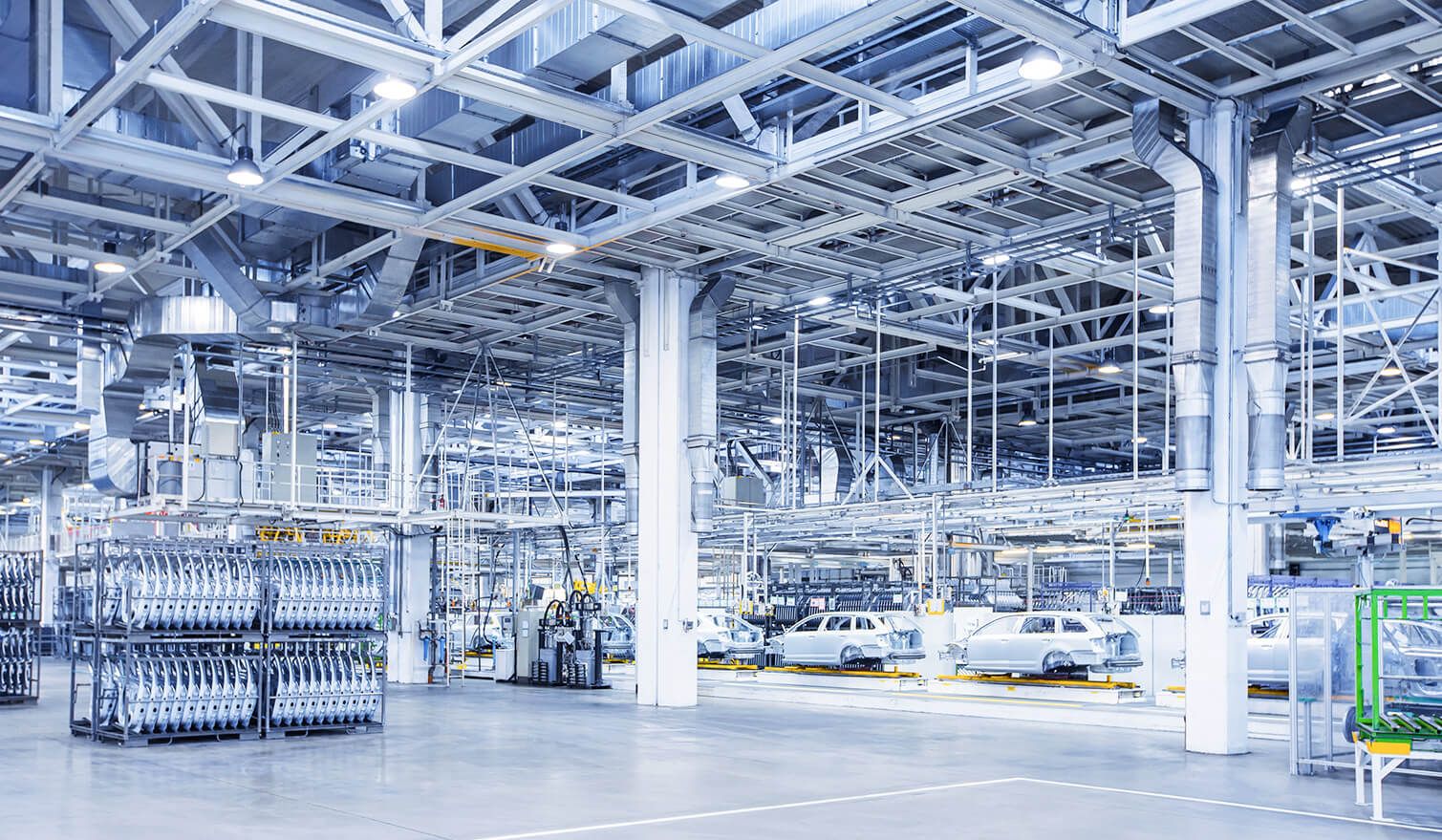 Grande usine abritant de nombreuses voitures et camions, mettant en évidence l'éclairage moderne dans le processus de production automobile