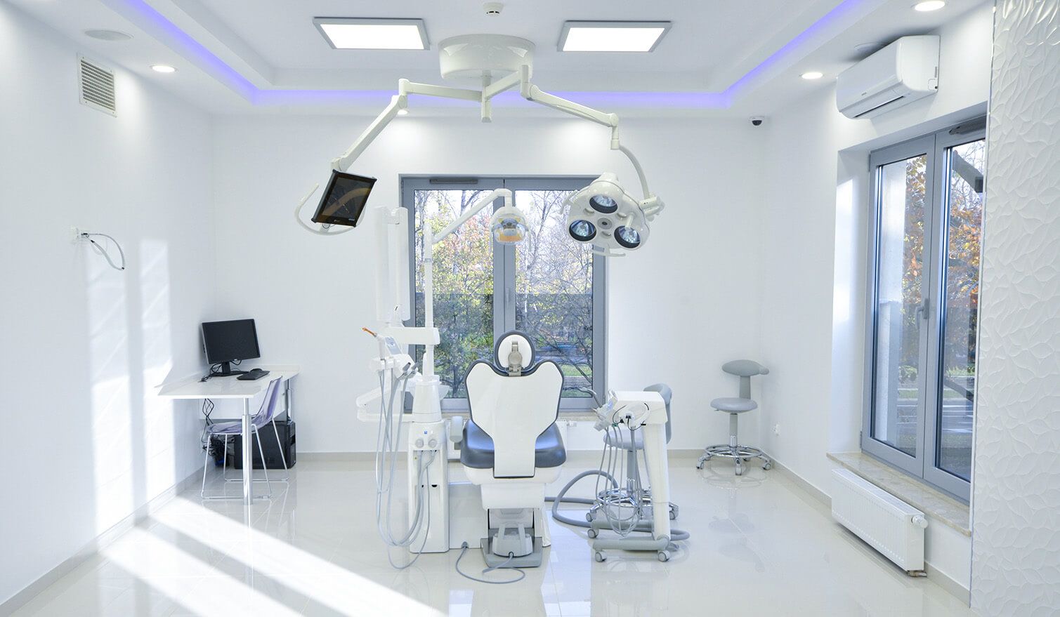 Intérieur d'un cabinet dentaire avec un fauteuil, un ordinateur et une lampe, soulignant l'importance d'un éclairage adapté en dentisterie | Lumedic