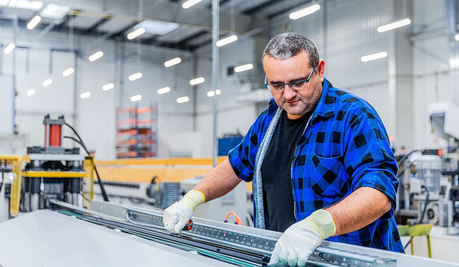 Un homme travaillant devant une machine dans une usine, concentré sur l'assemblage précis de composants électroniques