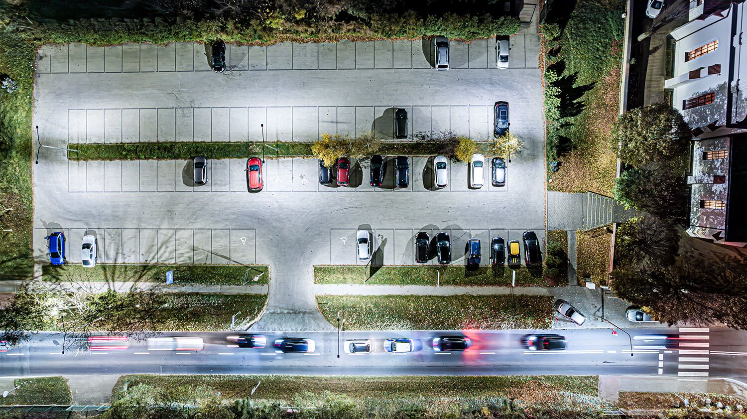  Widok parkingu z pojazdami, podkreślający rolę opraw oświetleniowych w zapewnieniu bezpieczeństwa i funkcjonalności.